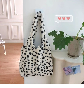 Detail of plush cow print tote bag with black and white checkered lining and soft fur texture