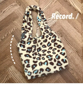 Detailed top view of leopard print plush tote bag with magnetic closure and plaid lining
