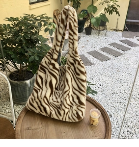 Close-up of fluffy tiger print tote bag made of soft plush material on a wooden table