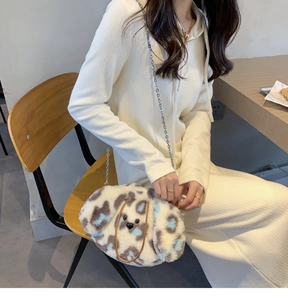 Detail of furry puppy shoulder bag with blue leopard spots and fine metal chain strap