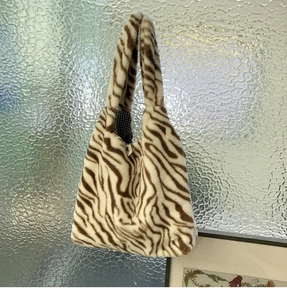 Detail view of the brown zebra print plush tote with metal snap and checkered lining