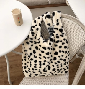 Detail of plush cow print tote bag showing blue checkered lining and magnetic closure