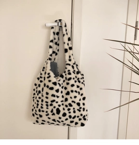 Detail of plush cow print tote bag showing soft faux fur texture and checkered inner lining