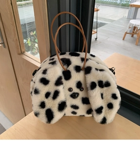 Detail of spotted plush puppy handbag with soft faux fur texture and brown leather handles