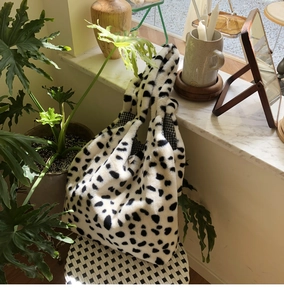 Close-up of plush cow print tote bag with spacious interior and checkered lining texture