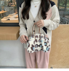 Close-up of leopard print plush handbag with soft faux fur texture and brown handles