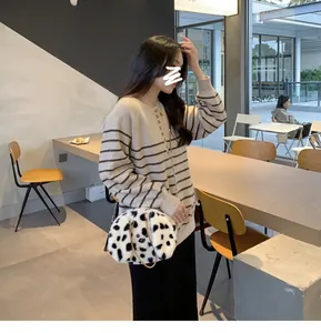 Close-up of black and white spotted plush shoulder bag with fine metal chain strap