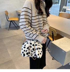 Detailed side view of a fluffy dalmatian dog plush crossbody bag with silver chain strap