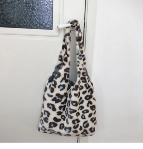 Detail of soft leopard print plush tote bag showing inner checkered lining and fuzzy texture