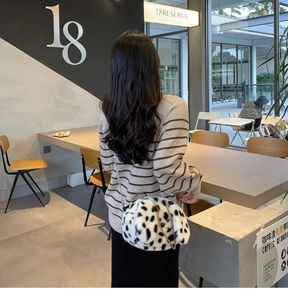 Detail of plush dalmatian print handbag with chain strap shown on a model in a cafe