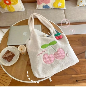 Detail of white lamb velvet tote bag with cherry embroidery and matching plush charm