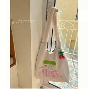 Detail of white plush tote bag featuring red cherry embroidery and 3D fruit pendant