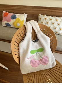 Close-up of white plush tote bag featuring pink plaid cherry embroidery and inner lining