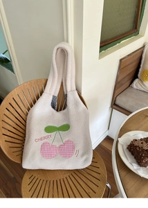 Detail of plush lamb wool tote bag featuring embroidered pink cherry and blue plaid lining