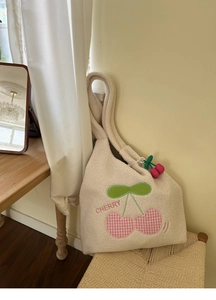 Detail of white sherpa tote bag with cherry embroidery and matching plush charm