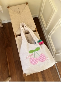 Close-up of fluffy white lamb wool tote bag featuring cherry embroidery and plush charm