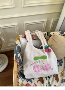 Detail of plush lamb wool tote bag featuring a pink checkered cherry patch and embroidery