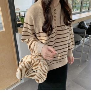 Detail view of a soft brown striped plush puppy handbag paired with a knit sweater