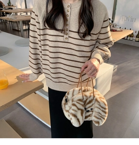 Chic autumn style with striped sweater and plush patterned animal handbag in cafe setting