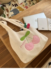 Close-up of white fleece tote bag with plaid cherry embroidery and plush pendant
