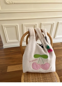 Detail of white plush tote bag featuring pink cherry embroidery and checkered lining
