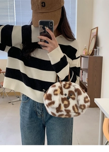 Detail shot of leopard print plush handbag with soft faux fur texture and animal face design