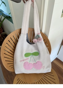 Detail of white fleece tote bag featuring heart cherry embroidery and black checkered lining