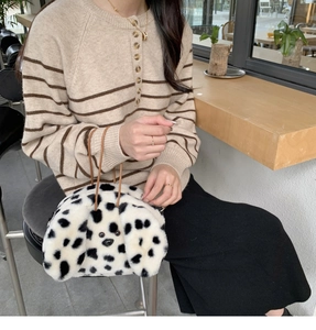 Chic dalmatian plush handbag with leather straps worn by model in a cozy cafe setting