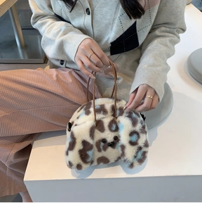 Detailed view of the fuzzy leopard print dog-shaped plush handbag with leather handles