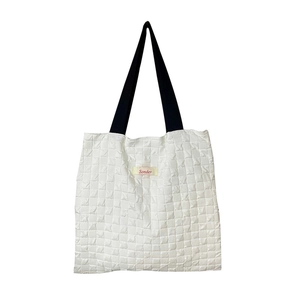 Quilted white tote bag with black shoulder straps and red Sonder label on the front