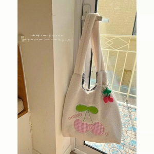 Cute sherpa tote bag with pink cherry embroidery and plush cherry charm in warm light