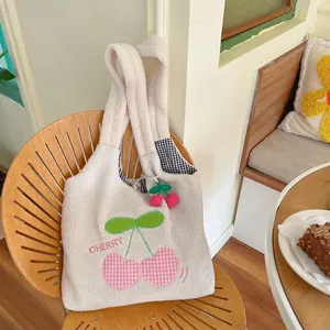 Plush lamb wool cherry embroidered tote bag with cute 3D charm on a wooden chair