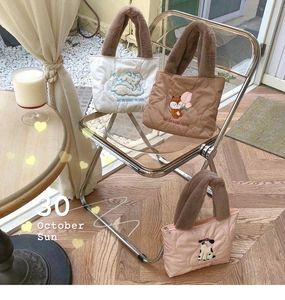 Macro view of quilted fabric handbag featuring animal embroidery and fuzzy plush handles