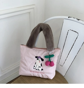 Detail of pink quilted handbag with puppy embroidery and plush handles on a chair