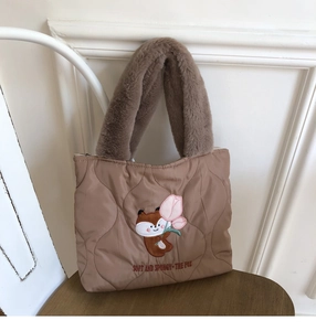 Quilted brown handbag with fox embroidery and plush handle on a wooden stool