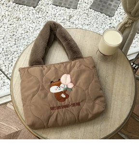 Detailed close-up of brown quilted bag with fox embroidery and plush fur handle