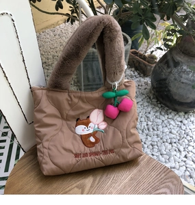 Detail of quilted tote bag with cute cartoon fox embroidery and faux fur handle
