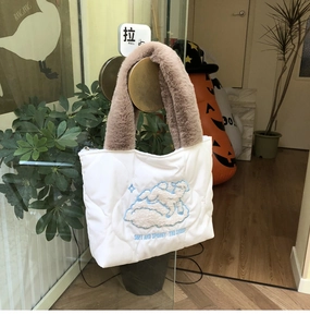 Detail of white quilted handbag featuring sheep embroidery and brown faux fur handles