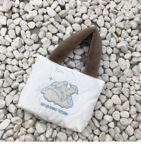 Close-up of white quilted tote bag featuring sheep embroidery and plush brown handles