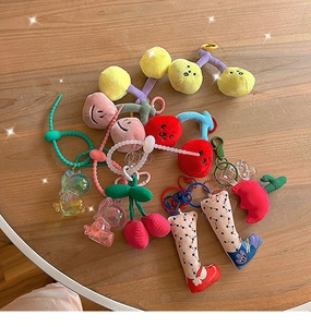 Flachbild von bunten Kirsch-Plüsch-Anhängern und Acryl-Anhängern auf einem runden Holztisch