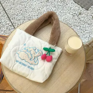 Quilted white cotton handbag featuring cute sheep embroidery and cherry charm on a table