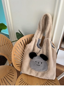Close-up of fluffy faux rabbit fur tote bag with cute dog patch on a wooden chair