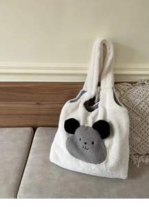 Close-up of plush tote bag with grey animal patch and checkered fabric lining