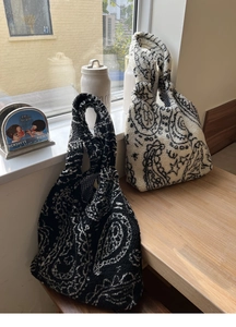 Close-up of black and white paisley plush tote bags showing thick fleece texture and details
