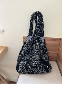 Close-up of black and white paisley fleece tote bag showing thick texture and checkered lining