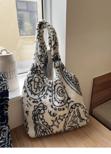 Detailed view of paisley faux shearling tote bag with checkered lining and soft texture