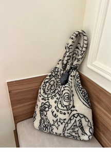 Detail of bohemian plush tote bag featuring black paisley patterns and checkered lining