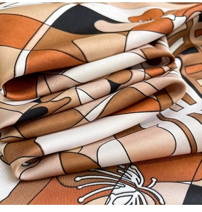 Macro shot of the diagonal twill texture and geometric floral print on the silk scarf