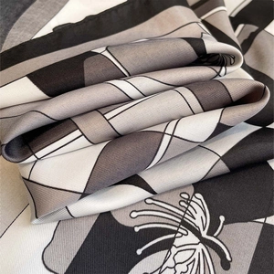 Close-up detail of geometric floral pattern and twill texture on a soft silk scarf