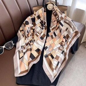 Elegant earth-tone geometric silk scarf draped on black top with luxury accessories